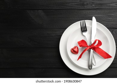 Beautiful table setting on black wooden background, top view with space for text. Valentine's Day dinner