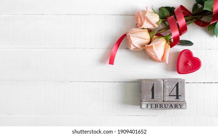 Wooden perpetual calendar on date February 14, candle-heart and a bouquet of roses. Concept Valentine's Day. Copy spase