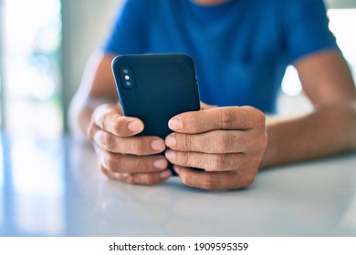 Young irish man smiling happy using smartphone sitting on the table at home.