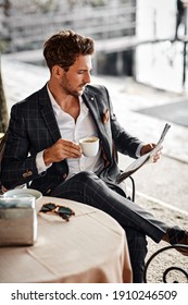 Handsome man drinking coffee and reading newspaper in cafe