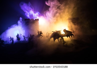 Fantasy-Kampfszene mit Drachen, die nachts eine mittelalterliche Burg angreifen. Kampf zwischen Drachen und heldenhaften Soldaten. Kreative Tischdekoration. Selektiver Fokus