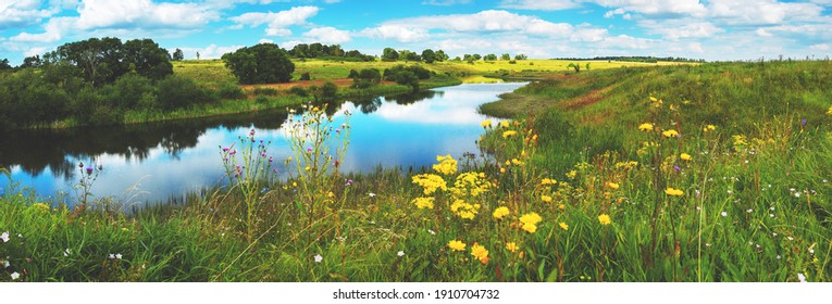 Schöne Sommer- oder Frühlingspanoramalandschaft mit ruhigem Fluss und grünen Hügeln mit blühenden Wildblumen und Bäumen am sonnigen Sommertag.Fluss Upa in der Region Tula, Russland.