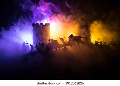 Fantasy-Kampfszene mit Drachen, die nachts eine mittelalterliche Burg angreifen. Kampf zwischen Drachen und heldenhaften Soldaten. Kreative Tischdekoration. Selektiver Fokus