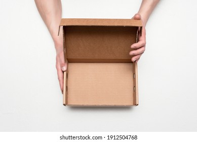 Empty cardboard box with copy space in the male hands on the gray background.