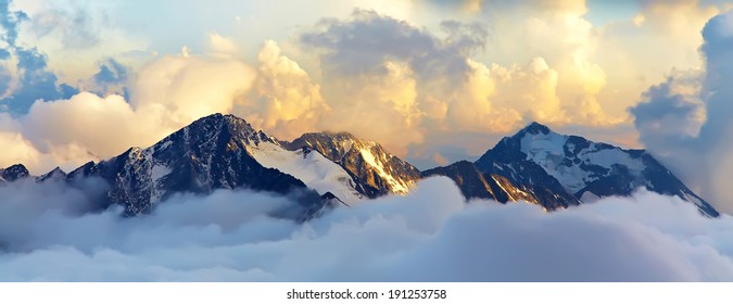 雪と雲に覆われた山頂のある高山の風景。バナー。パノラマ