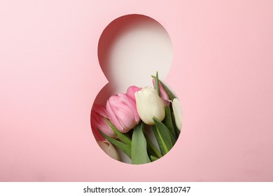 Scherenschnitt Acht aus rosafarbenem Hintergrund und Tulpen auf weißem Hintergrund