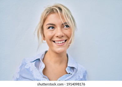 Junge blonde Frau lächelt glücklich und geht durch die Stadt.