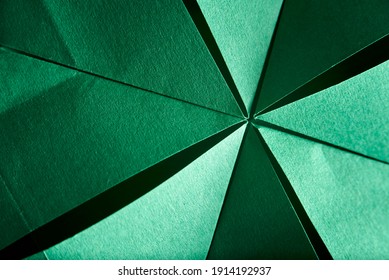 Abstract radial green background of folded textured paper. Close-up image. Concepts: origami, color, lines and geometry.