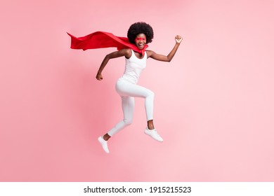 Chiều dài đầy đủ kích thước cơ thể xem của cô gái năng động vui vẻ nhảy mặc trang phục anh hùng chạy vội vội vàng bị cô lập trên nền màu hồng phấn