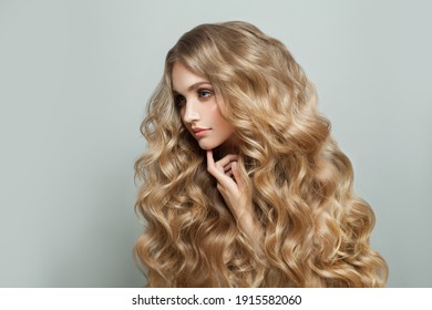 白い背景の上の長いブロンドの健康的な巻き毛のヘアスタイルとかなり若いブロンドの女性の髪のモデル