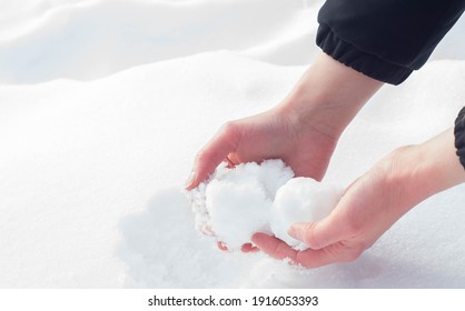 Kaukaskie dłonie formujące kulę śnieżną ze świeżego śniegu zimą w Europie. Ciesząc się zimną śnieżną pogodą po zmianie klimatu Bestii ze Wschodu.