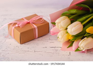 Holiday banner. Bouquet of pink and white tulips with gift box on light old background. Mothers day, Valentines Day, Birthday celebration concept. Copy space for text, top view