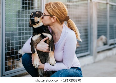 Mujer adulta joven sosteniendo un perro adorable en un refugio para animales.