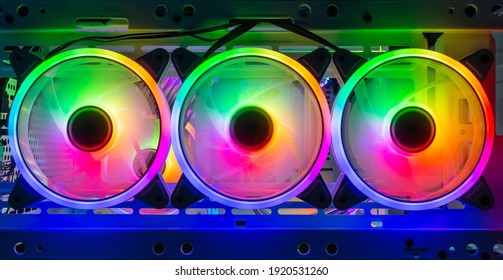 Drei bunte, helle Regenbogen-LED-RGB-PC-Lüfter-Luftgehäusekühler im weißen Desktop-Computergehäuse. Hintergrund des Gaming-Modding-Wasserkühlungs- und Technologiekonzepts