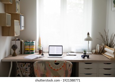 Lugar de trabajo de escritorio vacío en un acogedor dormitorio con portátil abierto, libros y papeleo. Mesa de madera grande y moderna con computadora y libros de texto, espacio de trabajo de estudiante o autónomo. Concepto de diseño.
