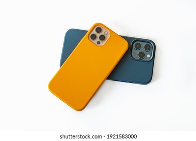 白地に青と黄色の革のケースで現代の携帯電話。トリプルレンズカメラを搭載した最新のスマートフォン