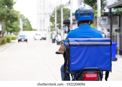 Leveringsmand iført blå uniform kørende motorcykel og leveringskasse. Motorcykel levering af mad eller pakkeekspresservice