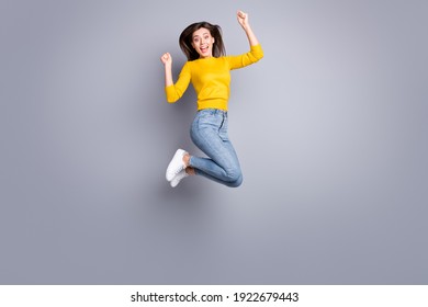 Foto de perfil de tamaño completo de la optimista dama morena agradable salto desgaste suéter amarillo jeans zapatillas aislado sobre fondo de color gris