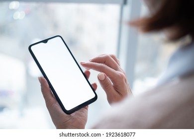 ウィンドウの背景からストリート ビューに空白の画面を持つ携帯電話を手に保持している女性