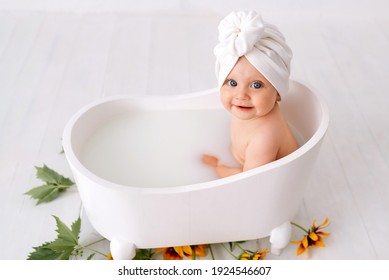 1歳の女の子がお風呂に入る。ブルーのスイミング キャップ。トイレ。女の子は洗面器で沐浴します。衣類はハンガーにかけて干します。バススクリーン。