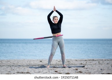 Young sporty woman is exercising with Hula hoop outdoors at the beach for healthy lifestyle concept.
