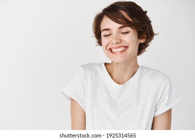 Portrait of happy and positive woman close eyes, smiling carefree, standing in t-shirt on white background.