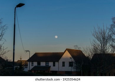 Una luna llena de virgo sobre las casas durante el anochecer