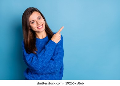 Foto de uma jovem bonita, sorridente, de bom humor e positiva, apontando o dedo, com espaço para texto, isolada em um fundo azul.