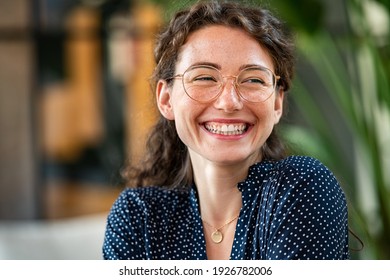 Portrait of laughing young woman wearing spectacles in office. Carefree casual girl wearing glasses and looking away. Confident beautiful student wearing specs and smiling.