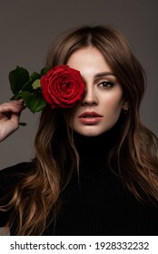 Portrait of a beautiful girl with a flower near the eyes. Red Rose. Black clothes.