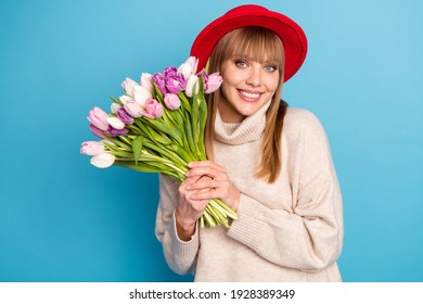 Foto von wunderschönen positiven Damenhänden, die Blumen halten, Lächeln, Blick, Kamera, isoliert auf blauem Farbhintergrund