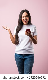 Pretty millennial indian girl isolated on pink studio background text messaging on cell phone or using smartphone with wireless connection