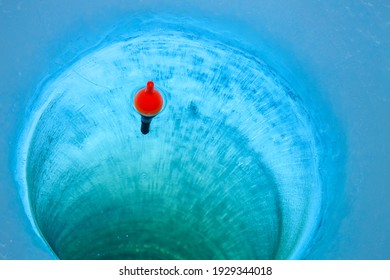 Red bobber and fishing line in an ice fishing hole in a Minnesota lake