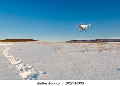 Drone volando sobre el campo cubierto de nieve en el soleado día de invierno