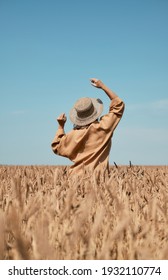 Happy girl in a hat dancing in a field on a clear blue sky background.