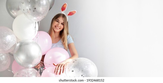 Frohe Ostern. Schließen Sie herauf Porträt des fröhlichen, hübschen Mädchens mit den lustigen Hasenohren und mit den rosa Luftballons an der Geburtstagsfeier auf grauem Hintergrund. Osterferienkonzept. Alles Gute zum Geburtstag Banner Platz für Text