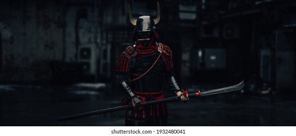 Seorang pemuda Eropa dengan kostum samurai ronin tradisional Jepang dengan pedang katana di latar belakang gelap dan di jalan. Cosplay dan Karnaval
