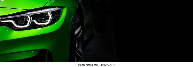 テキスト用の右側の黒い背景の空き領域に、LED テクノロジーを備えた詳細な緑の現代車のヘッドライトを閉じます。