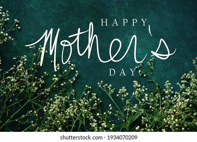 Elegant mother's day background with dainty flowers on green color backdrop.