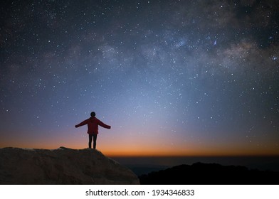 若い旅行者やバックパッカーのシルエットは、山の頂上で一人で星と天の川を見ました。彼は旅行を楽しんでおり、頂上に到達したときに成功しました。