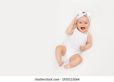 Em bé sơ sinh mỉm cười trên chiếc giường trắng ở nhà, khái niệm về một em bé hạnh phúc, khỏe mạnh, một nơi để văn bản
