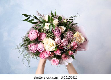 水色の背景、クローズアップの美しいバラの花束を持つ女性