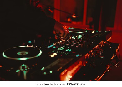 Dj playing music on rave party in nightclub.Professional disc jockey plays concert turntables,sound mixer devices on stage in dark night club.Royalty free curated collection with parties and concerts