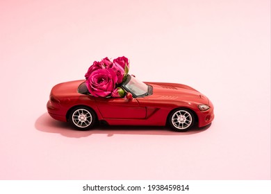 Primer plano de un coche con hermosas flores en el interior. Coche rojo parado sobre un fondo rosa con rosas dentro el 8 de marzo para una niña. Regalo elegante para el 8 de marzo para tu novia.