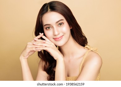 アジアの女性は、完璧で清潔な健康な肌と美しい長い茶色の髪に満足しています。かわいい女性モデルのきれいなみずみずしい肌。表情豊かな表情。美容コンセプト。