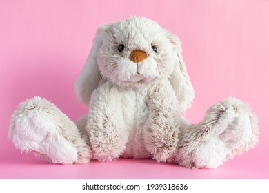 Conejito de peluche sobre fondo rosa. Concepto de Pascua. Lindo conejito de juguete sentado sobre fondo de color.
