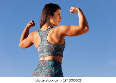 sportvrouw pronkt met haar biceps en rugspieren