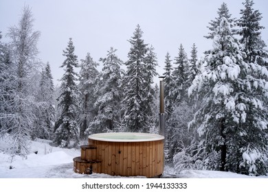 Un jacuzzi de madera cerca de un bosque de invierno en un día de nieve, Kroderen, Noruega