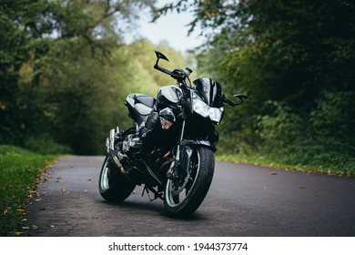 Black sports motorcycle standing on a forest road on a background of green trees
