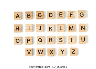 Tampilan atas alfabet Inggris yang terbuat dari ubin kayu persegi dengan alfabet Inggris tersebar di latar belakang putih dengan spasi untuk teks. Konsep pengembangan berpikir, tata bahasa.